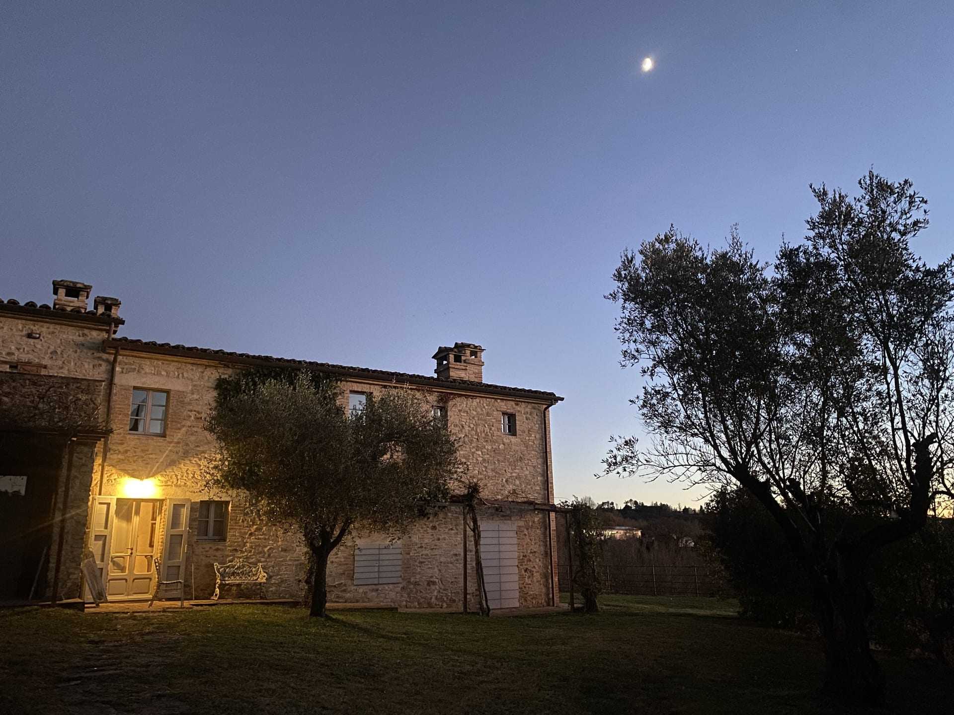 Il casale in pietra visto dal giardino, nella luce della sera